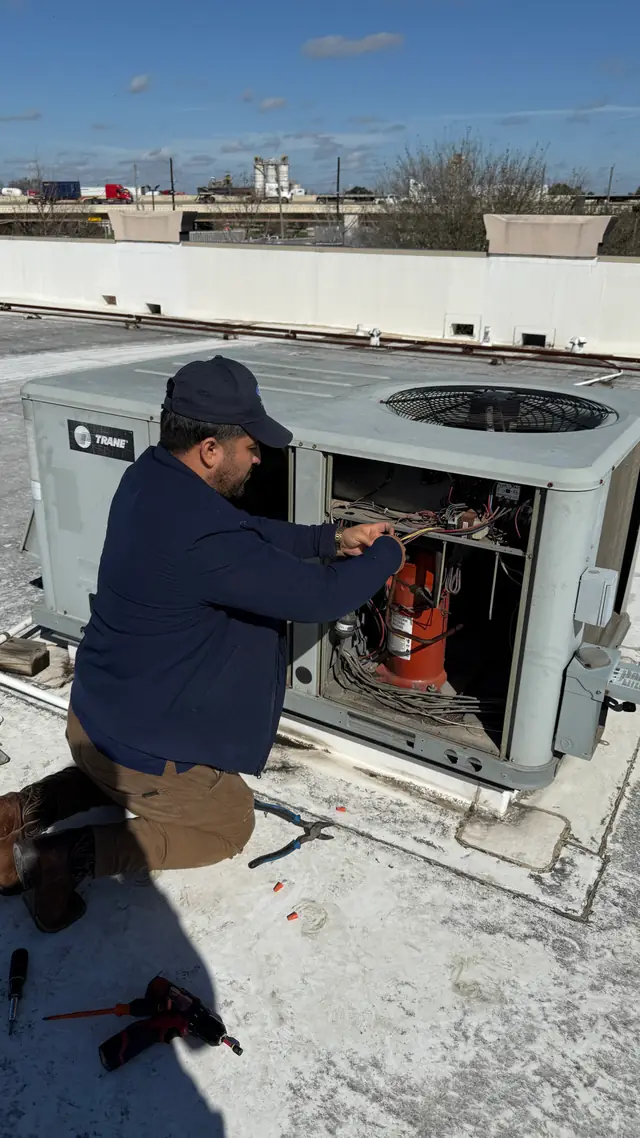 Prime Texas Air technician servicing a rooftop packaged unit with the access panel removed